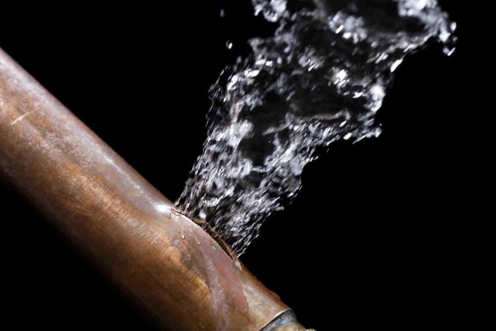 An old pipe bursting water against a black background