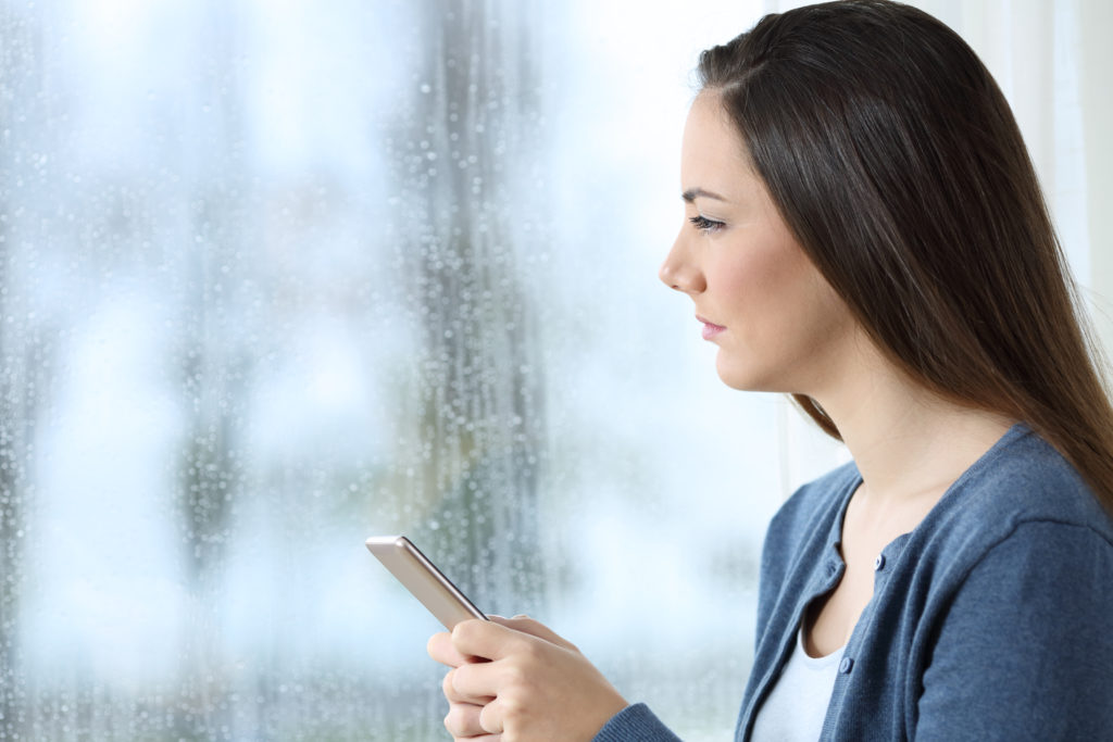 A woman checks her phone during rain.