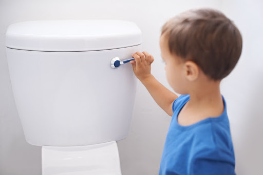 A child flushing a toilet.